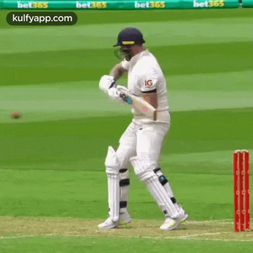 a cricket player is swinging a bat at a ball on a cricket field .