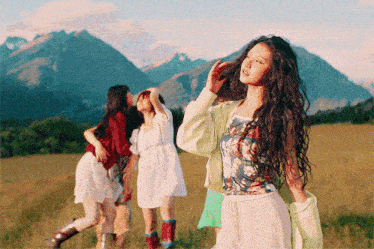 a woman with long hair stands in a field with other women