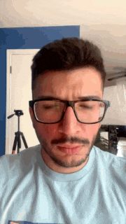 a man wearing glasses and a blue shirt is making a face