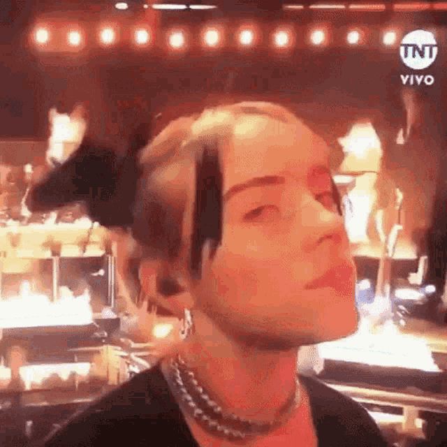 a close up of a woman 's face with a ponytail and a necklace .