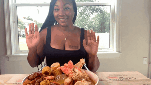 a woman sitting at a table with a plate of food and a box that says crab claw