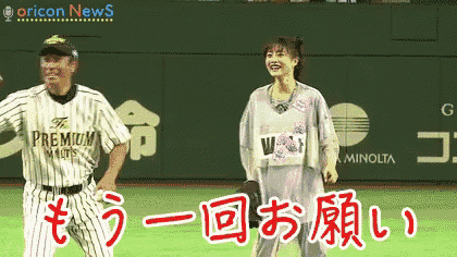 a man and a woman are dancing on a baseball field in front of an oricon news sign