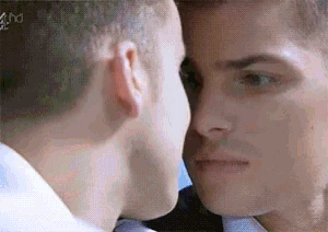 two men are touching each other 's faces in front of a mirror .