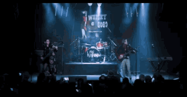 a band performs on stage with a sign that says whisky a gogo