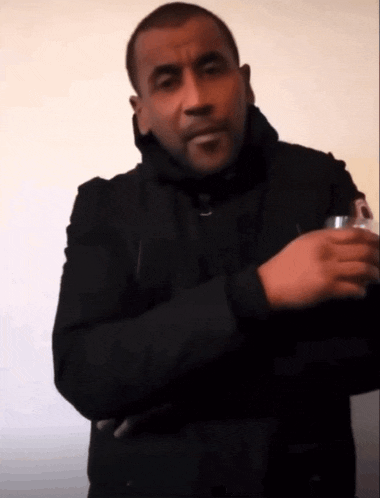 a man in a black jacket is holding a can of soda in his hand