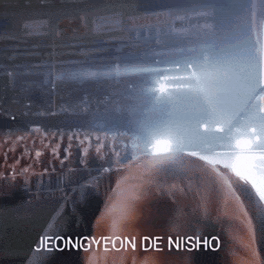 a person sitting in front of a crowd with the words jeongyeon de nishio written on the bottom