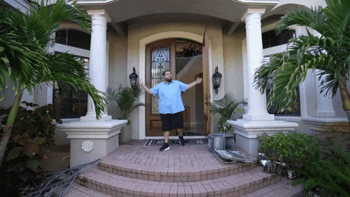 a man in a blue shirt is standing in front of a house