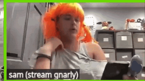 a woman wearing an orange wig is sitting in front of a computer .