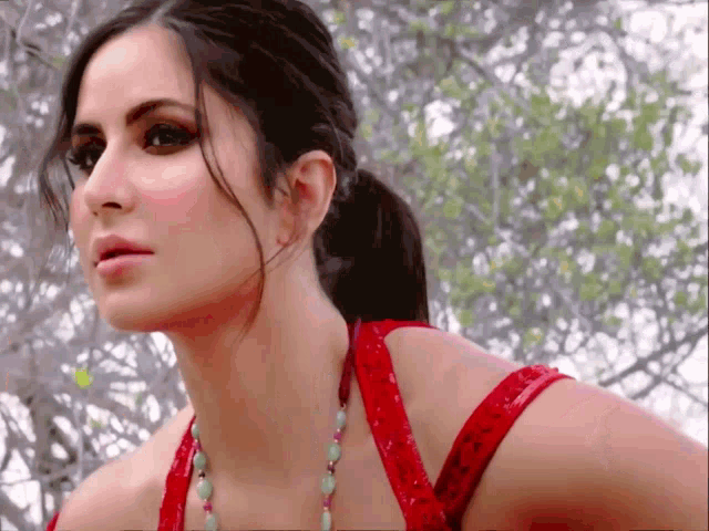 a close up of a woman 's face wearing a red top and necklace