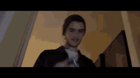 a young man wearing a beanie and a black jacket is standing in front of a television in a dark room .