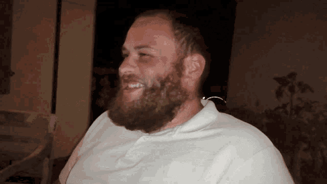 a man with a beard is wearing a white shirt and smiling