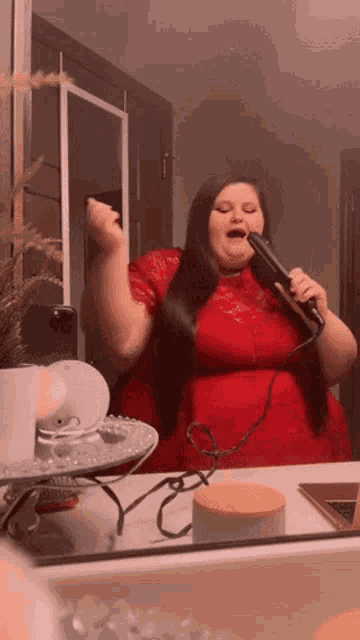 a woman in a red dress is blow drying her hair