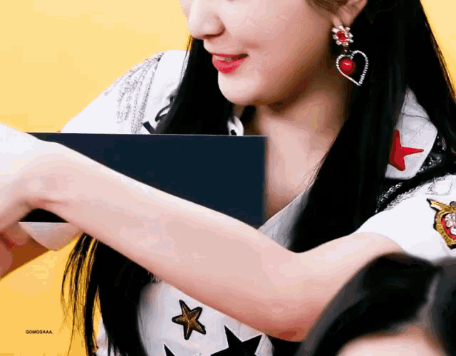 a woman wearing a heart shaped earring is holding a book
