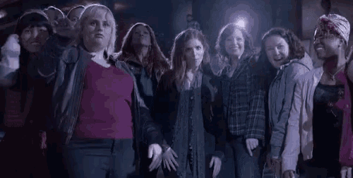 a group of women are standing next to each other in a dark room in front of a light .