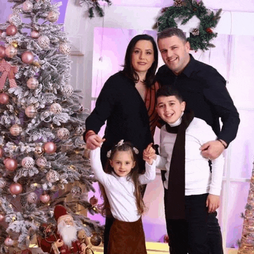 a family is posing for a picture in front of a christmas tree