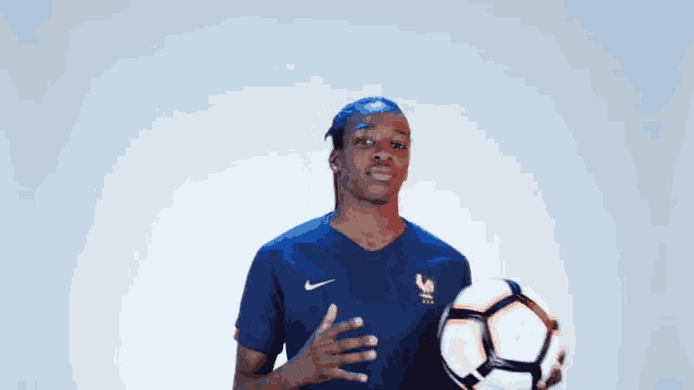 a woman in a blue nike shirt holds a soccer ball in her hand