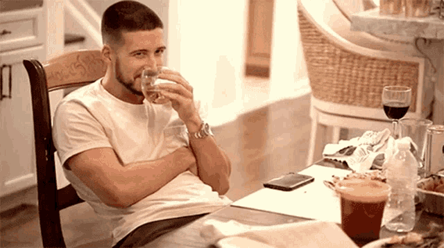 a man sits at a table drinking from a glass