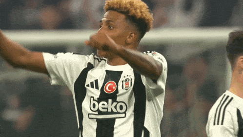 a soccer player wearing a black and white beko shirt