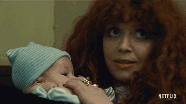 a woman with red hair is holding a baby in her arms with netflix written on the bottom