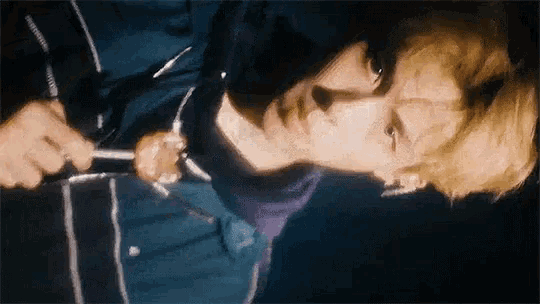 a man is holding a knife in his hand while laying down and looking at the camera .