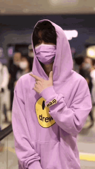 a man wearing a purple drew hoodie and a mask