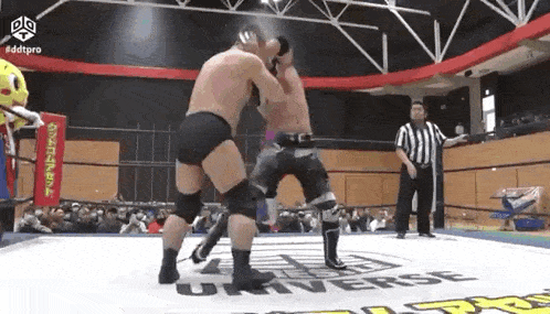 two men are fighting in a wrestling ring with a referee in the background .
