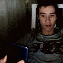 a man wearing headphones and a shirt with the letter g on it looks at his phone