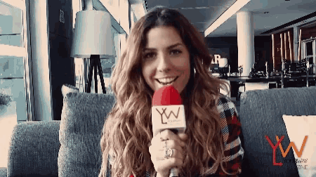 a woman sitting on a couch holding a microphone with xw written on it