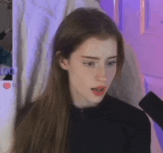 a young woman with long hair is sitting in front of a purple curtain .
