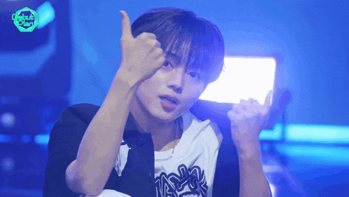 a young man giving a thumbs up in front of a sign that says ' tokyo ' on it