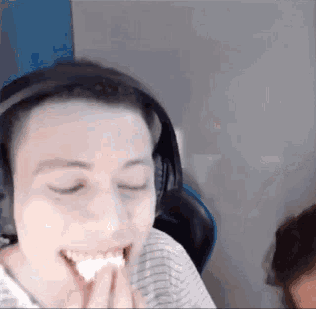 a man wearing headphones is laughing and eating a piece of food .
