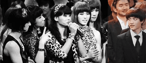 a group of people are standing next to each other in a crowd and one of them is wearing a leopard print dress .