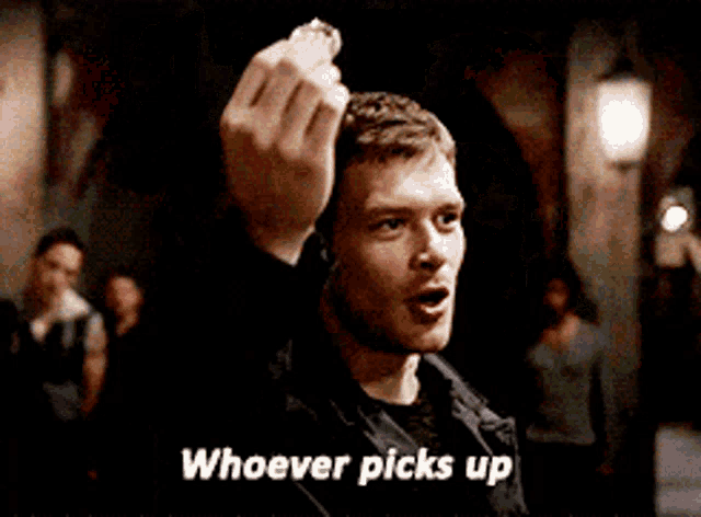 a man in a black jacket is holding something in his hand and says " whoever picks up "
