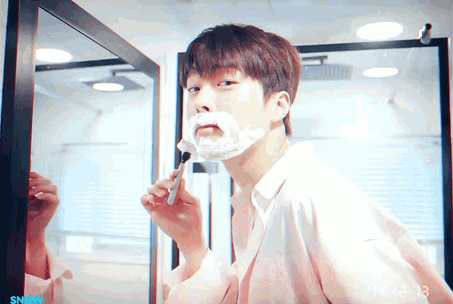 a man shaving his face in front of a mirror with the time of 14:43