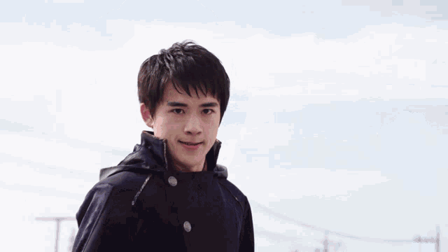 a young man in a black jacket holding a green object