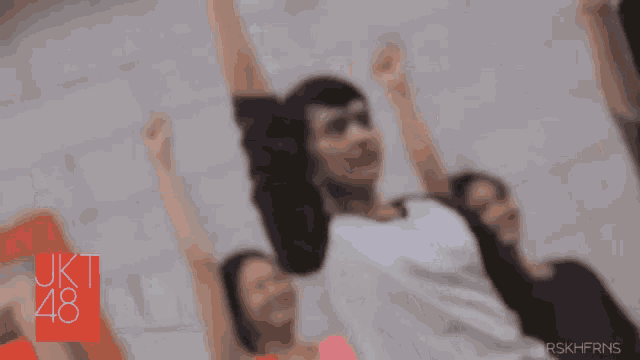 a woman is laughing in front of a sign that says jkt 48
