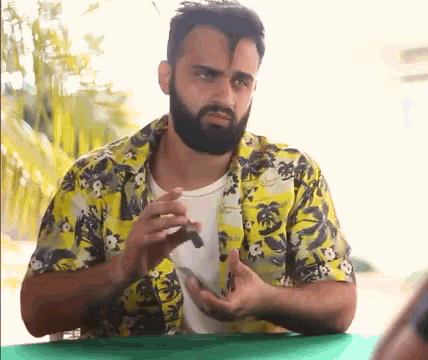 a man with a beard is wearing a yellow shirt with palm trees