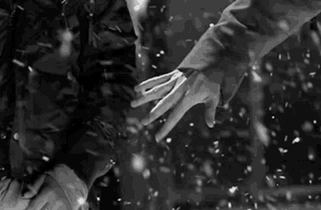 a black and white photo of a person holding hands in the snow .