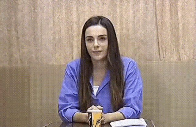 a woman in a purple shirt sits at a table