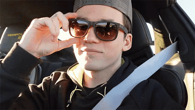 a man wearing sunglasses is sitting in a car with a nascar logo on the side
