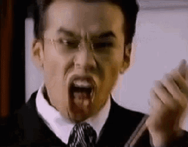 a man with blood coming out of his mouth is wearing glasses and a tie .