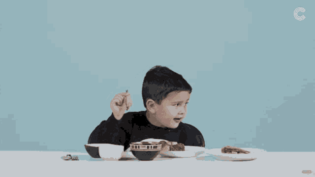 a little boy sitting at a table with filipino food written on the screen