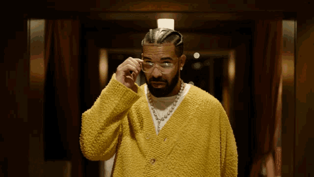 a man wearing a yellow sweater and glasses looks down