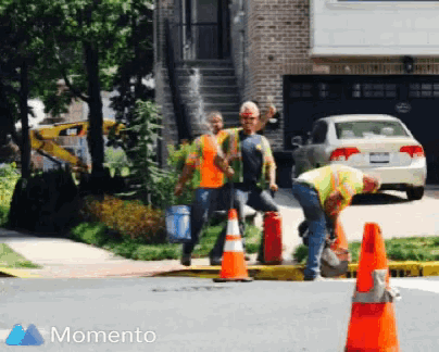 a group of construction workers walking down a street with the word momento in the upper right corner