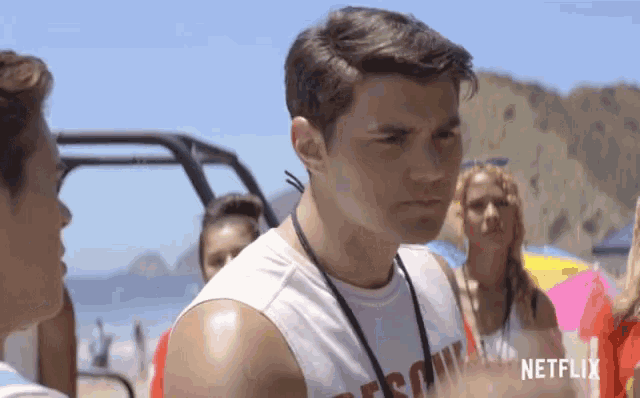 a man wearing a netflix shirt stands on the beach