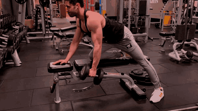 a man is lifting a dumbbell on a bench in a gym with the word grays in the background