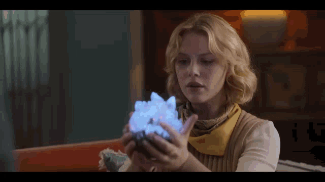 a woman is holding a crystal in her hands and it is glowing blue