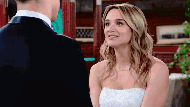 a woman in a wedding dress is smiling at a man in a suit