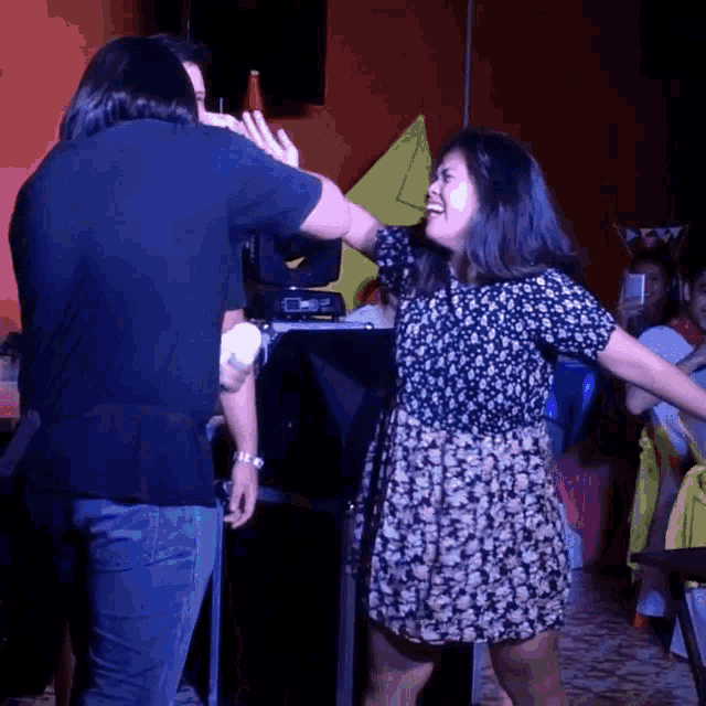 a woman in a floral dress is dancing with a man