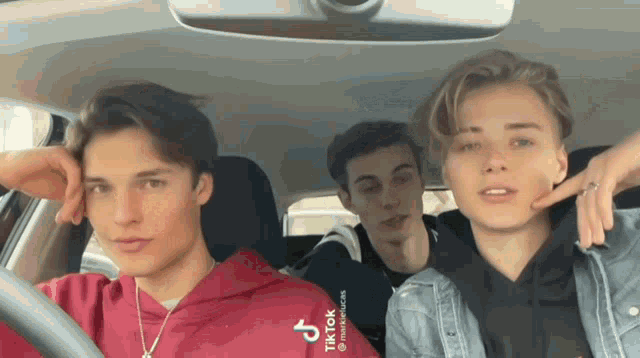 three young men are sitting in a car with tiktok written on the back of their shirt